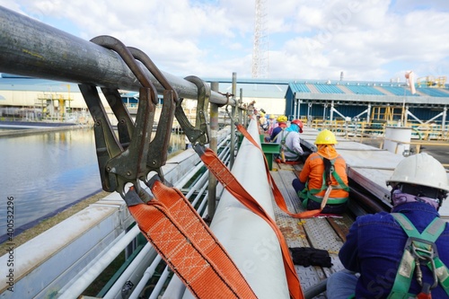 Hook of safety harness on scaffolding pipe during working at heights in construction site, Chemical plant.