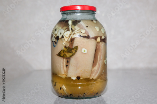 Salted lard in brine in jar with spices.