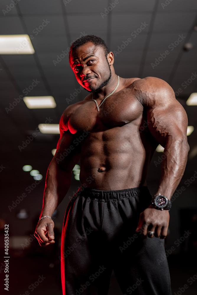 Athletic African American man with a bare torso posing and shows his muscles. Bodybuilding, posing, health, fitness, beauty.