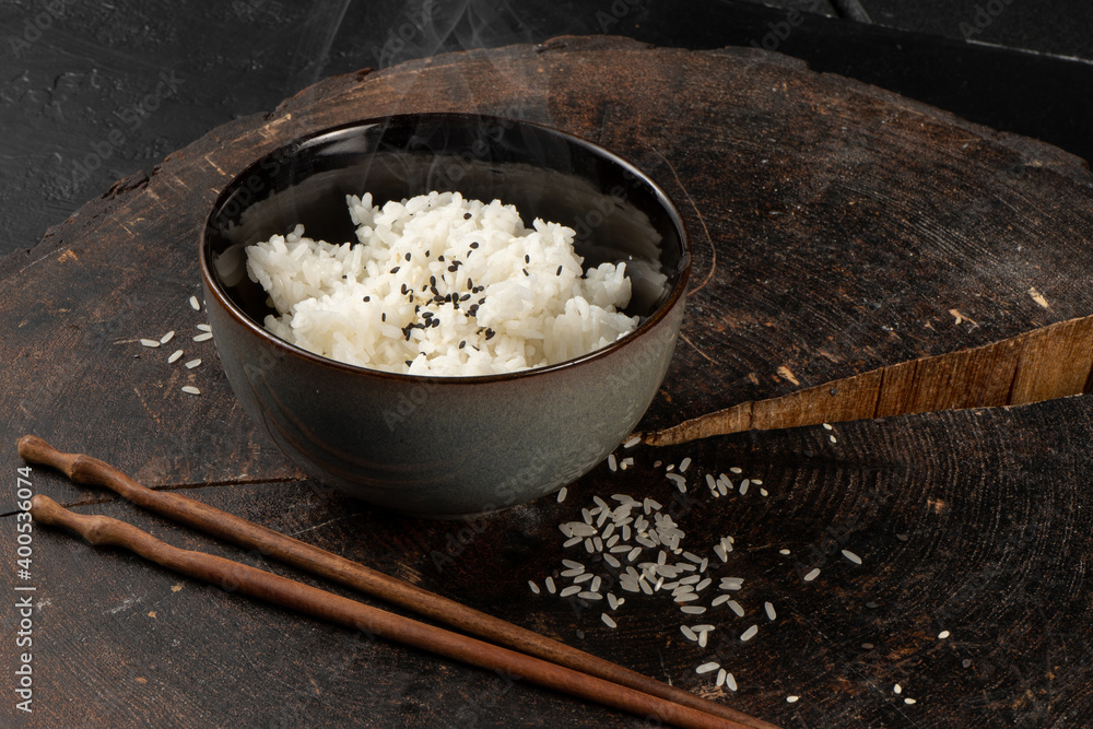 Sesame steamed rice in a deep ceramic bowl with wooden chopsticks. A classic hot oriental Asian dish.