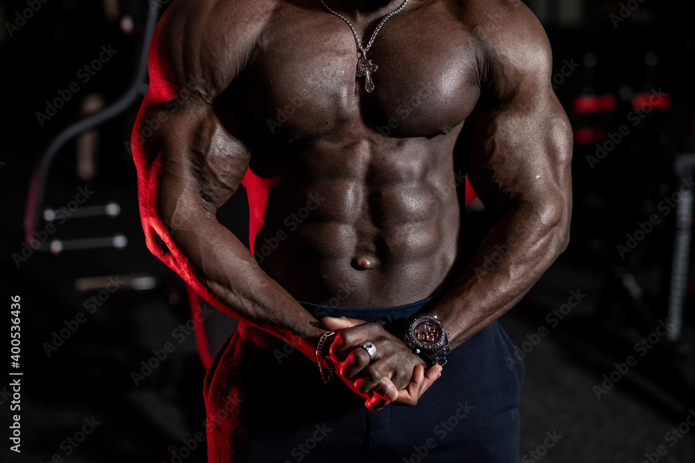 Selective focus on perfect male african american body. Male poses to the camera with strong hands and perfect abs.