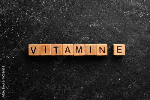 The inscription "VITAMIN E" is laid out of wooden cubes. Top view.