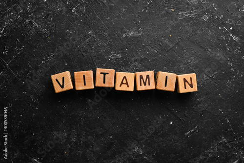 The inscription "VITAMIN" is laid out of wooden cubes. Top view.