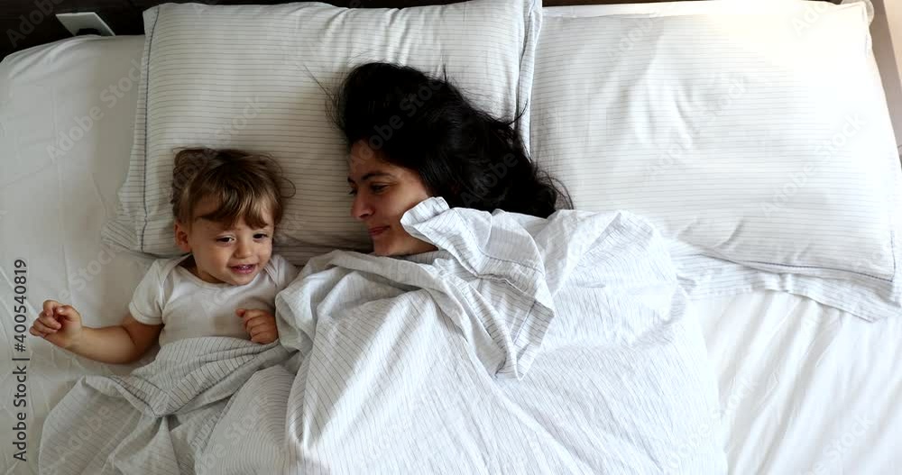 Mother and baby toddler in bed, morning top view perspective Mother and baby toddler in bed, morning top view perspective