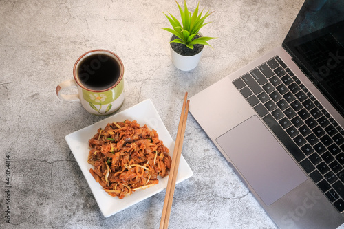 Laptop computer or notebook, char kuew tiaw and cup of coffee on working table with copy space . photo