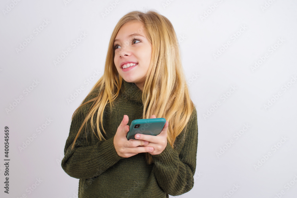 Copyspace photo of Caucasian kid girl wearing green knitted sweater against white wall stupor with something occurring in social media Copyspace photo of Caucasian kid girl wearing green knitted sweater against white wall stupor with something occurring in social media
