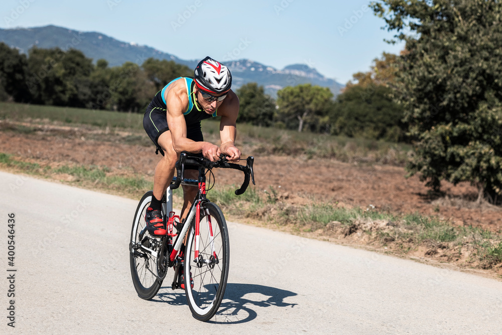 Fototapeta premium Cyclist with helmet and sunglasses riding a bike in a rural road