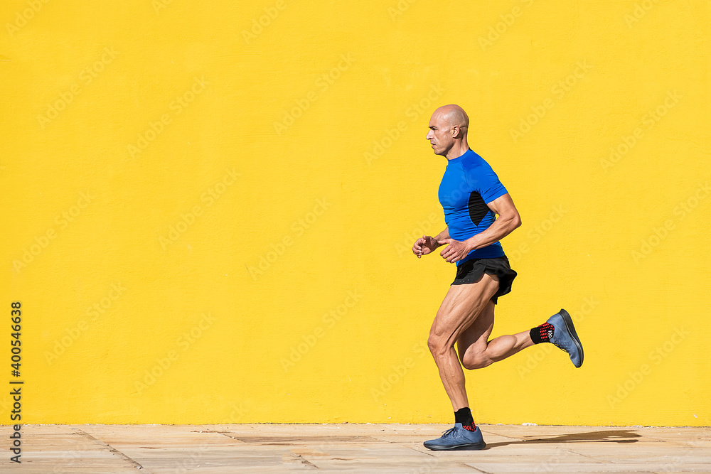 Sportsman running in the street with a yellow background Sportsman running in the street with a yellow background