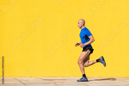 Sportsman running in the street with a yellow background