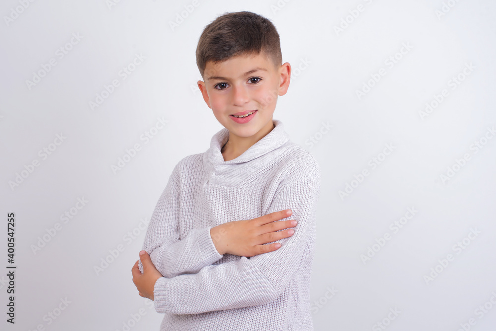 Cute Caucasian kid boy wearing knitted sweater against white wall happy face smiling with crossed arms looking at the camera. Positive person. Cute Caucasian kid boy wearing knitted sweater against white wall happy face smiling with crossed arms looking at the camera. Positive person.