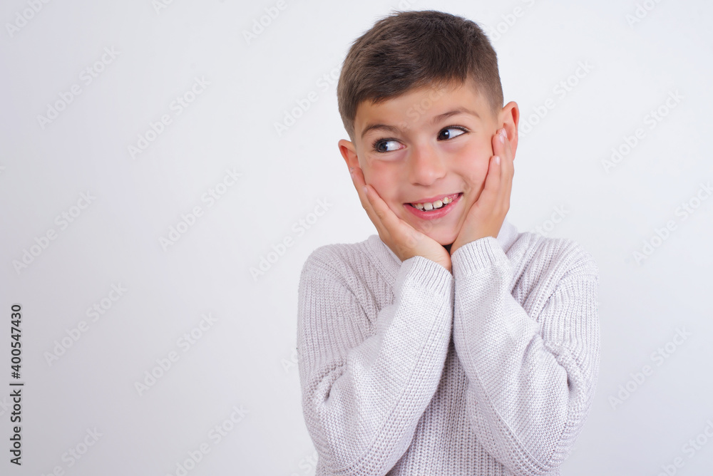 Inspired Cute Caucasian kid boy wearing knitted sweater against white wall looking at copyspace having thoughts about future events Inspired Cute Caucasian kid boy wearing knitted sweater against white wall looking at copyspace having thoughts about future events