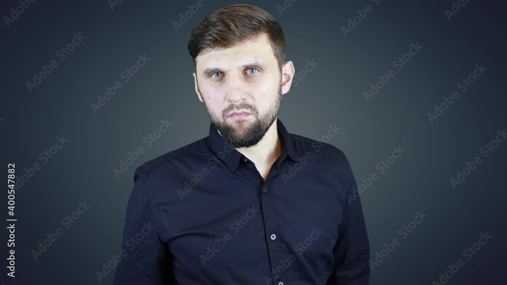 angry man in a shirt on a dark background turns and looks at the camera angry man in a shirt on a dark background turns and looks at the camera