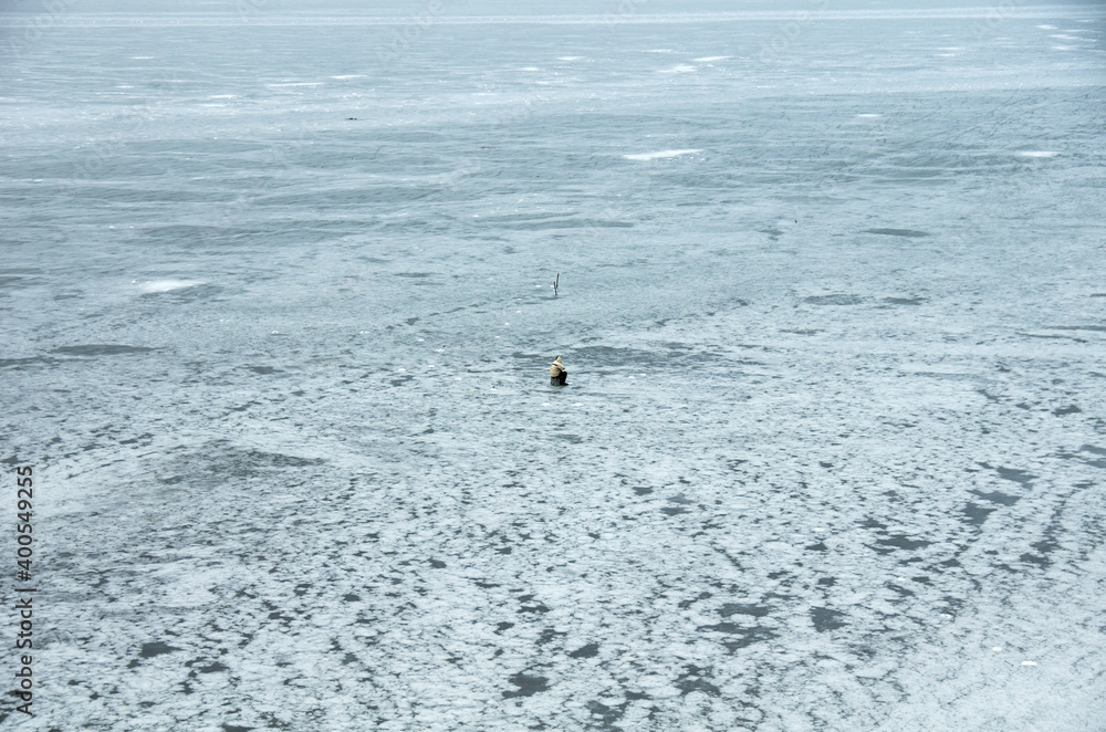 Winter fishing on a frozen lake. Lonely fishermen on the ice. Winter fishing on a frozen lake. Lonely fishermen on the ice.