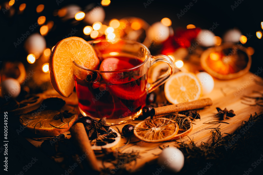 Christmas mulled wine, Drink with dried fruits and berries, Winter hot tea in a glass and spices on a wooden background. - obrazy, fototapety, plakaty 