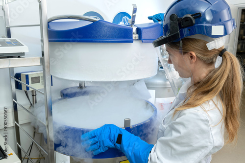 Kryokonservierung von Zellen und Gewebe im Stickstofflagertank, Biotechnologin öffnet Flüssigstickstoff Behälter.  photo