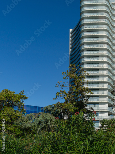 Beautiful view of resort town Sochi with tropical evergreens and part of luxury hotel on blue sky background. Sunny autumn day. Place for your text.