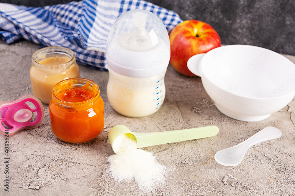 Bowl with vegetables puree and bottle of baby food on gray background Bowl with vegetables puree and bottle of baby food on gray background