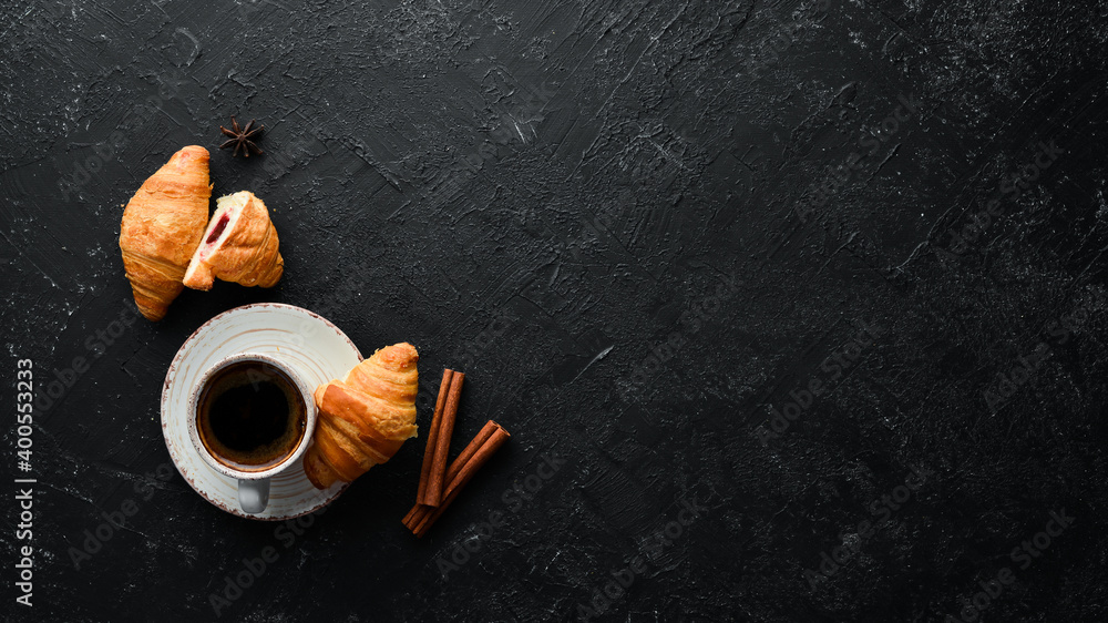 Cup of coffee with croissant. Breakfast. On a black stone background. Top view. Free space for your text.
