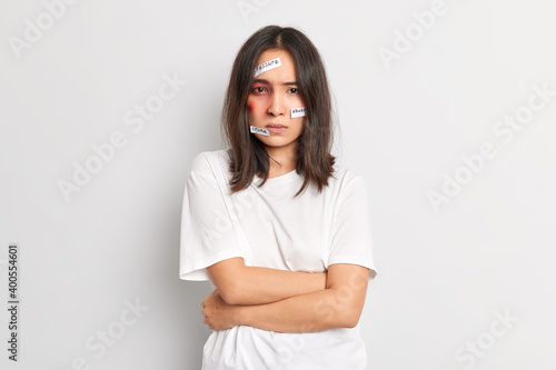 Image of abused young woman has dark bruise under eye keeps hands crossed over body tries to defense herself from cruelty and violence being brutally by violent aggressive husband suffers injury