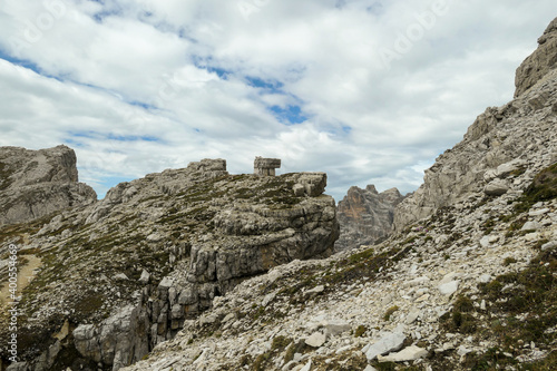 An endless view on a high and desolated mountain peaks in Italian Dolomites. The lower parts of the mountains are overgrown with moss and grass. Raw and unspoiled landscape. Few clouds above the peaks