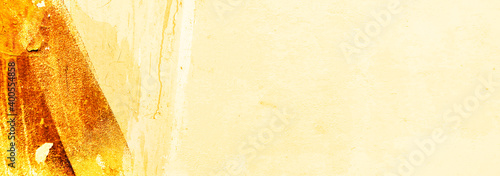 Brush strokes of yellow and orange color on the texture of old plaster on the wall. Horizontal bright sunny background looks like sepia background in yellow and brown tones.