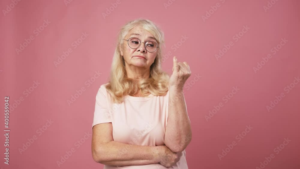 Senior lady in glasses deciding solution, counting on fingers from one to five, pink studio background Senior lady in glasses deciding solution, counting on fingers from one to five, pink studio background