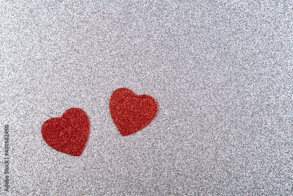 two red hearts in glitter on a silver glitter background two red hearts in glitter on a silver glitter background