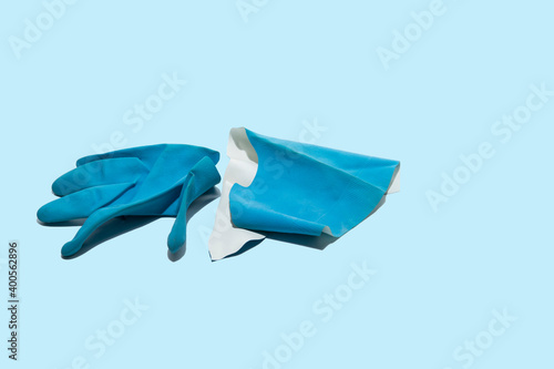 Worn, torn blue medical glove on a light blue background. Health professionals work under very difficult conditions.