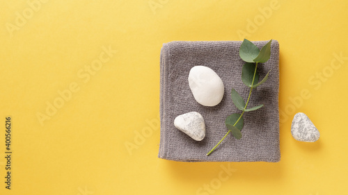 Trendy colors of the year 2021. Illuminating Yellow and Ultimate Gray. spa background with towel, eucalyptus branch and zen like stones. top view. copy space. banner