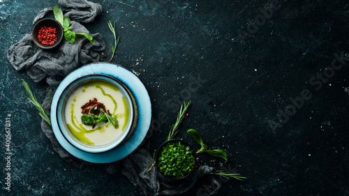 Healthy food. Creamy soup with bacon and basil in a plate on a black stone background. Top view. Rustic style.