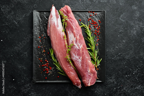 Meat. Raw pork tenderloin with spices on a black stone background. Top view. Rustic style.