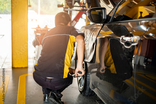 car automobile mechanic working on repairing the wheel tire of vehicle, taking car in for service workshop for male car mechanic fixing problems replacing broken parts of using tools and equipment © Have a nice day 