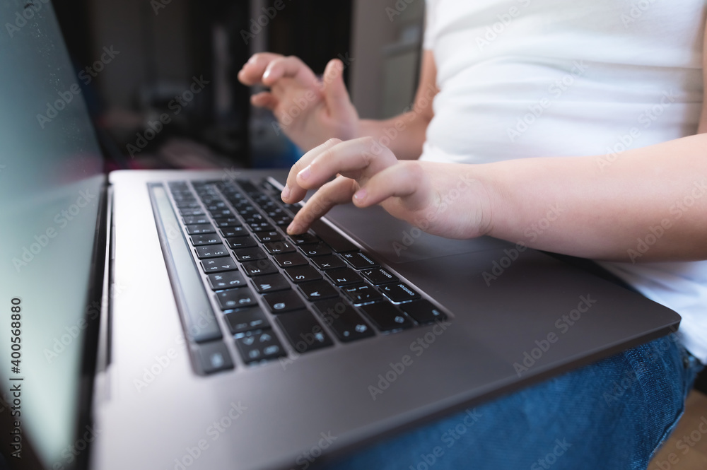 Closeup shallow depth of field of a little girl's hand on a laptop keyboard. The concept of using the younger generation of gadgets Closeup shallow depth of field of a little girl's hand on a laptop keyboard. The concept of using the younger generation of gadgets