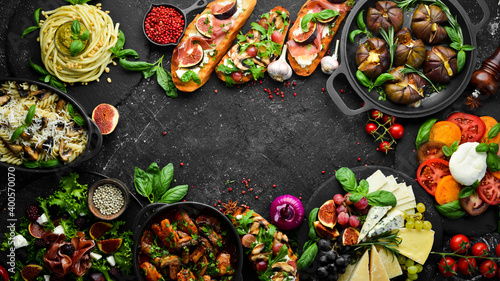 Food: cheese, figs, mushrooms, meat and vegetables. European and Asian cuisine. Healthy food on a black stone background. Top view.