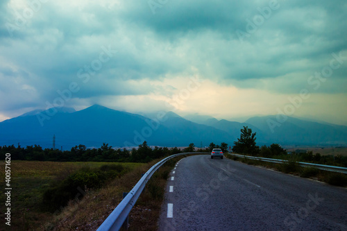 Scenic landscape with Pirin mountain range, outgoing road with lonely bicycle and thunder clouds background. Bulgaria.