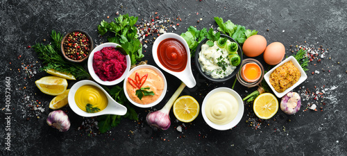 Set of sauces and spices on stone background. Sauces: mayonnaise, ketchup, tartare, barbecue and chili sauce in bowls. photo