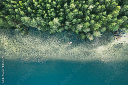 Aerial view of blue lake with a fishing boat and green forests