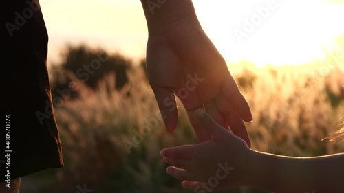 Close-up of mother and daughter hands joining together with sunset sunlight flare in natural background, Slow motion. Beautiful romantic moment between mother and litle child. Happy Family and Relatio