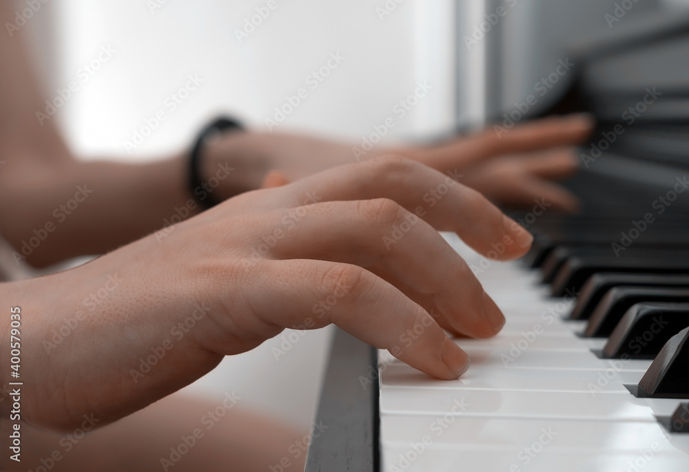 Obraz premium Piano private lesson. Young woman teaches a kid to play the piano. Playing together. Master teaches a boy to play piano. Concept of the music study and arts. Close-up. No faces.