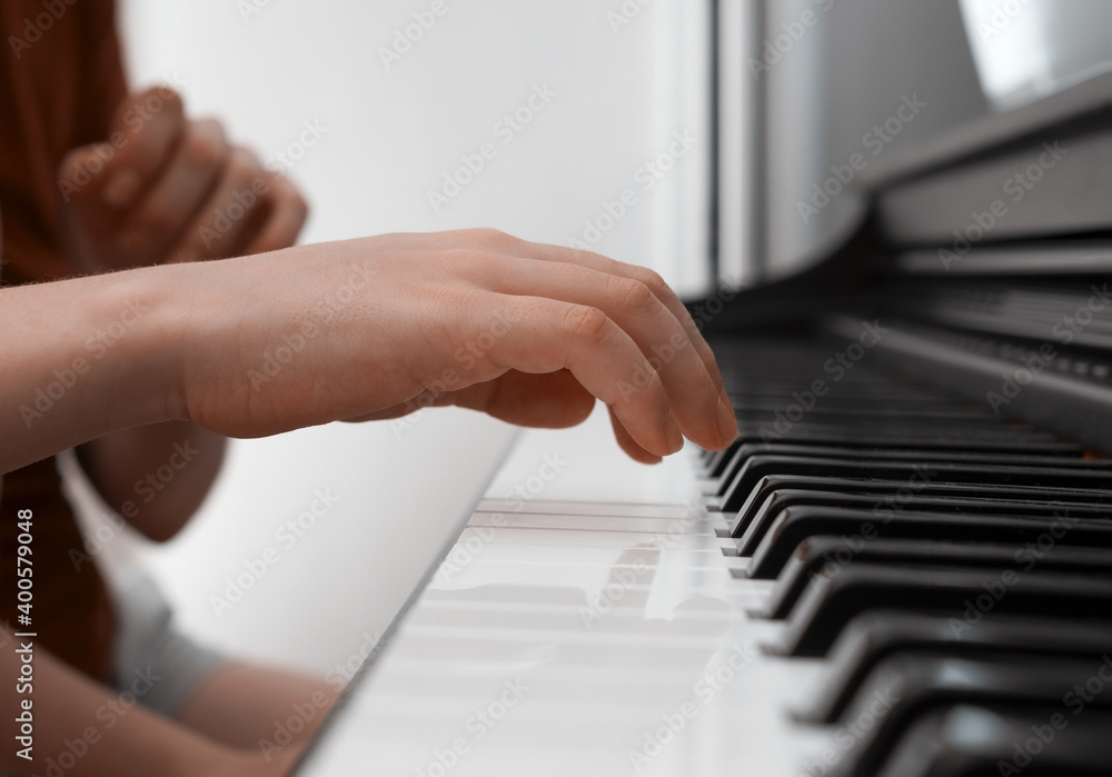 Obraz premium Piano private lesson. Young woman teaches a kid to play the piano. Playing together. Master teaches a boy to play piano. Concept of the music study and arts. Close-up. No faces.