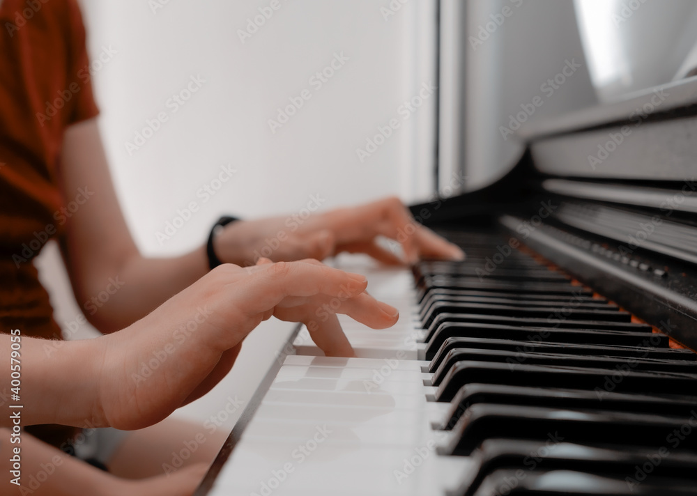 Obraz premium Piano private lesson. Young woman teaches a kid to play the piano. Playing together. Master teaches a boy to play piano. Concept of the music study and arts. Close-up. No faces.