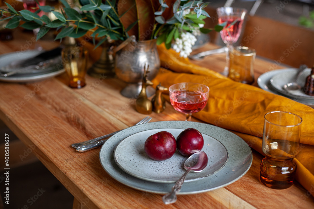 long wooden party table with stylish decoration, with candlesticks, vases of flowers, glasses with wine, plates and food in a room with a white brick wall long wooden party table with stylish decoration, with candlesticks, vases of flowers, glasses with wine, plates and food in a room with a white brick wall