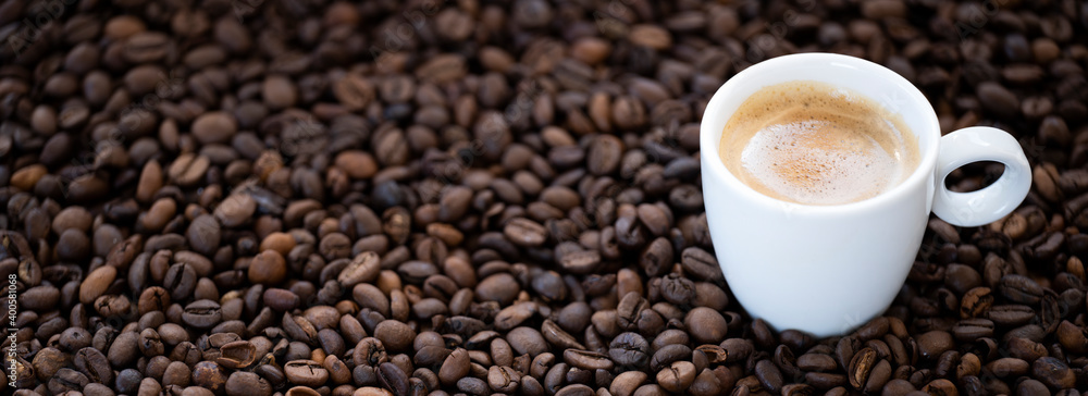 Fototapeta premium Flat lay with copy space, (selective focus) A white espresso cup with some creamy coffee is placed on some roasted coffee beans.