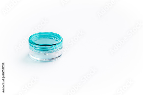 Empty small plastic or glass jar for beauty cream on white background. Close transparent container with a blue lid. Acrylic container for skin care cosmetics.
