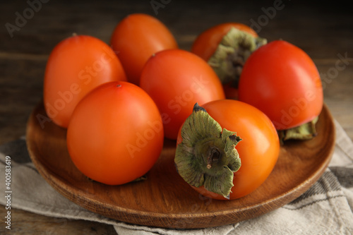 Foto Tasty ripe persimmons on wooden table, closeup