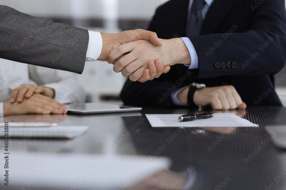 Handshake as successful negotiation ending, close-up. Unknown business people shaking hands after contract signing in modern office