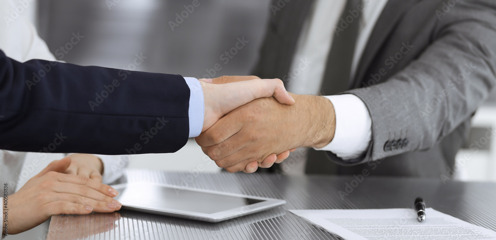 Handshake as successful negotiation ending, close-up. Unknown business people shaking hands after contract signing in modern office Handshake as successful negotiation ending, close-up. Unknown business people shaking hands after contract signing in modern office