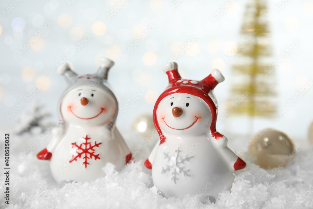 Christmas composition with decorative snowmen on artificial snow against blurred festive lights Christmas composition with decorative snowmen on artificial snow against blurred festive lights