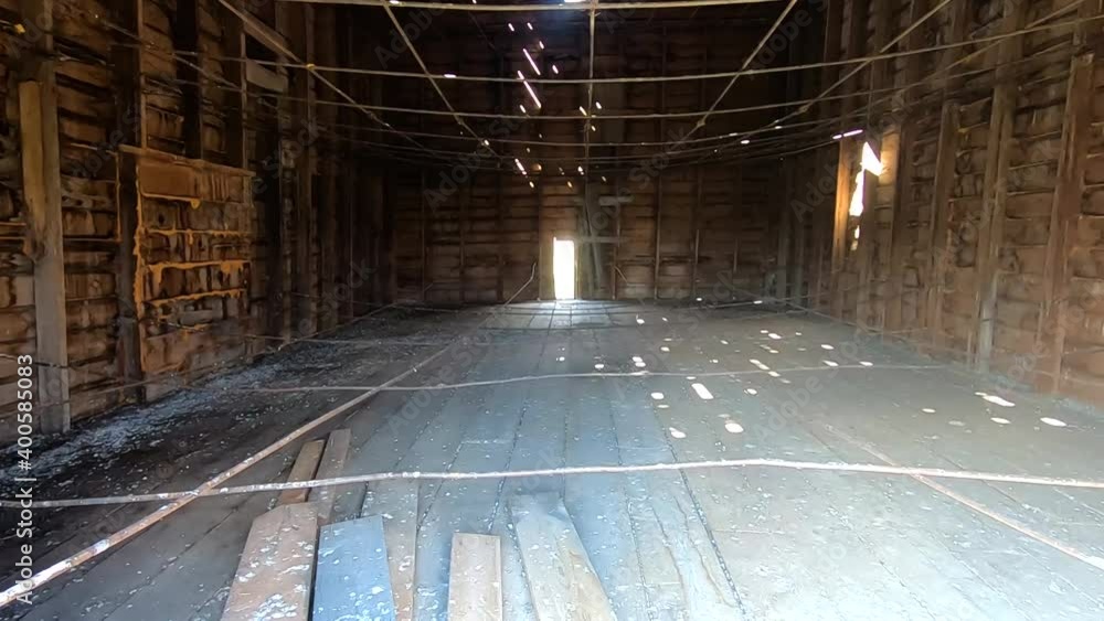 Inside a old dirty abandoned barn with beams hanging from the walls ...