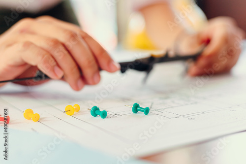 The pin on blue print and blur Engineering hands hold vernier caliper working and checking drawing blue print scale on workplace.